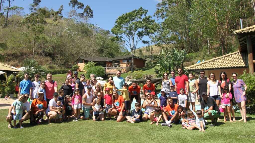 Grupo de famílias e amigos reunido ao ar livre no Parador Maritacas durante uma hospedagem em grupo.