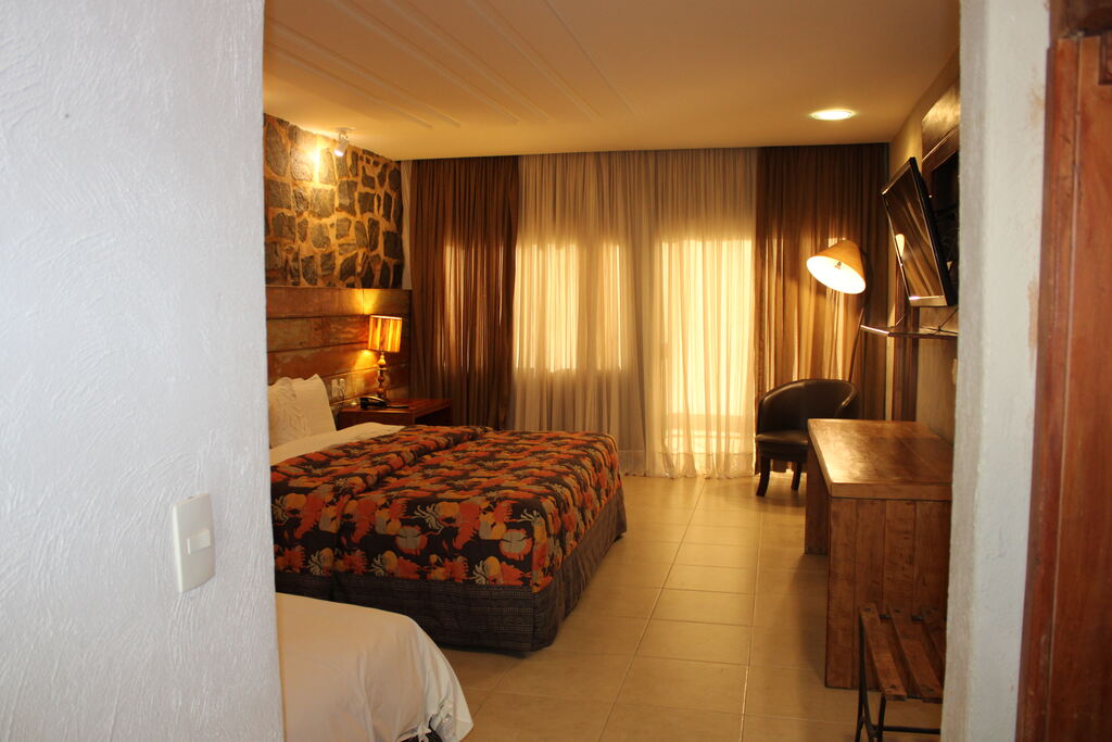 Quarto espaçoso e confortável de hotel fazenda para família, com cama de casal, decoração rústica e ambiente aconchegante.