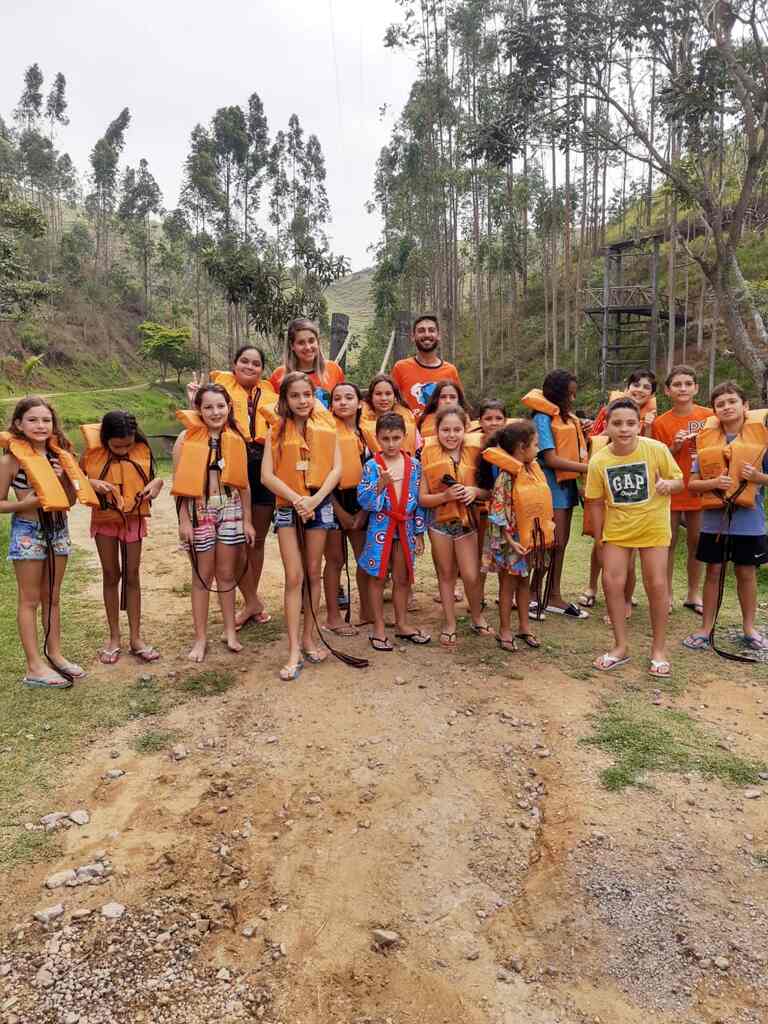 Crianças participando de atividades de recreação ao ar livre em hotel fazenda para família, com monitores e contato com a natureza.