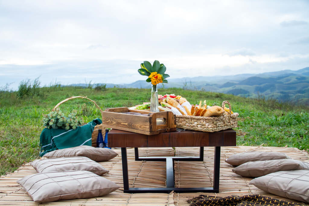 Picnic ao ar livre com cesta de alimentos em meio à natureza para uma viagem curta em casal.