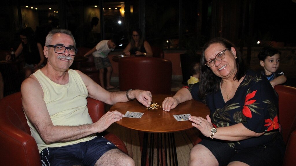 Casal maduro joga bingo em área de convivência do Hotel Fazenda Parador Maritacas durante momento de lazer.