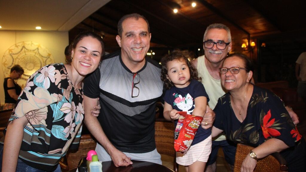 Família reunida em momento de lazer durante uma whycation no campo, com criança no colo e ambiente acolhedor.